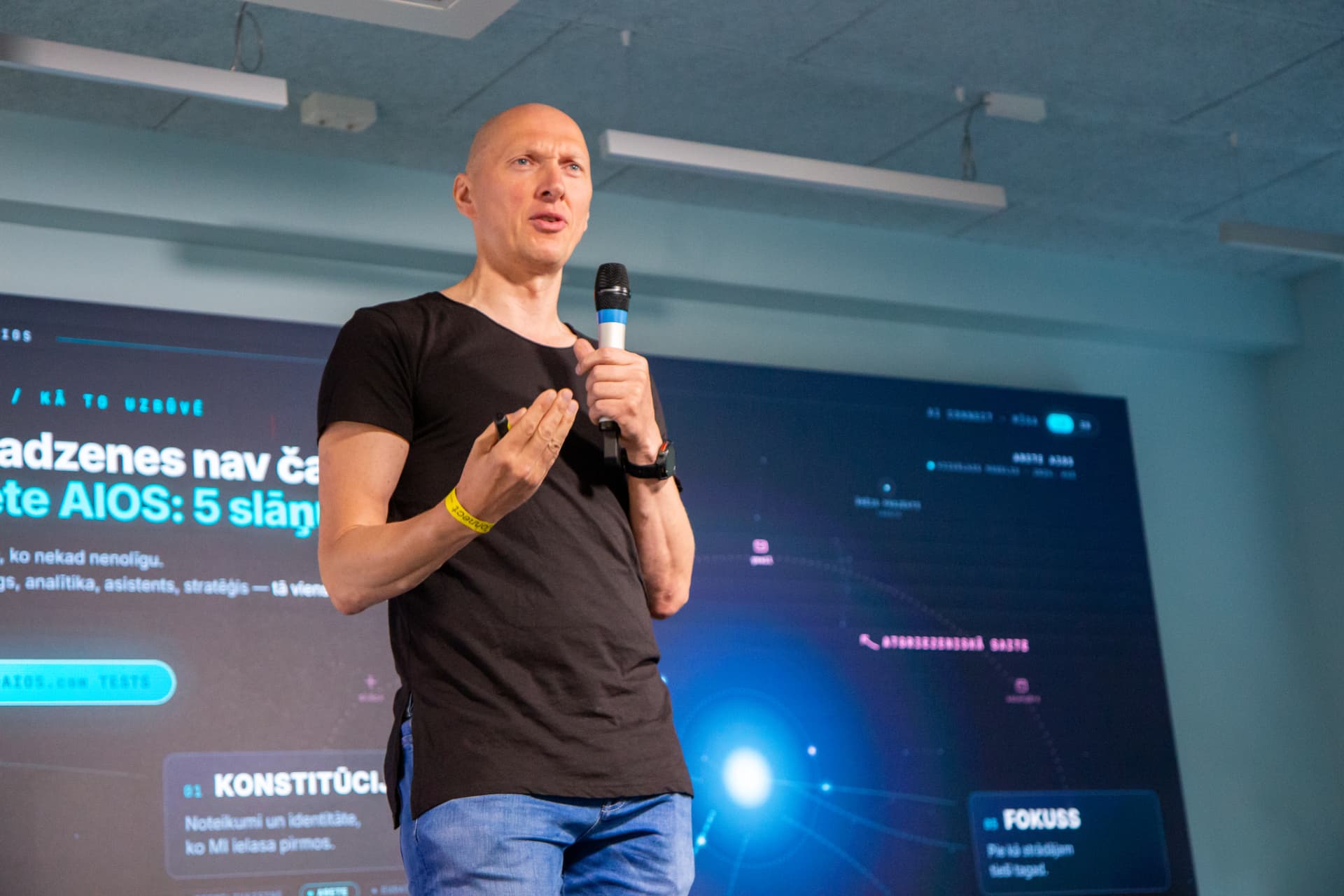 Speaker presenting on stage in front of a slide